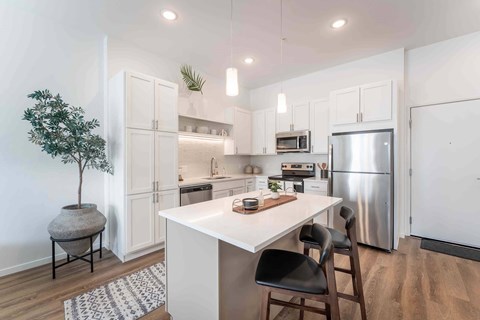 A kitchen with a white table and black chairs.