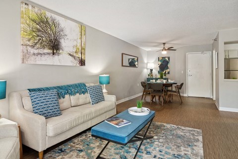 A living room with a white couch, a blue coffee table, and a painting on the wall.