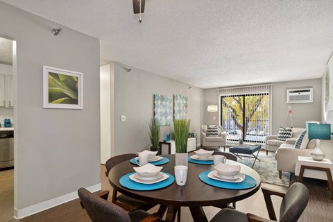 A dining room with a table set for two and a couch with a blue cushion.