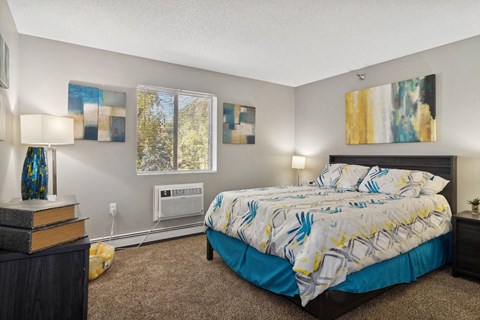A bedroom with a bed, nightstand, and two wall art pieces.