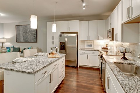 A kitchen with white cabinets and a granite countertop.