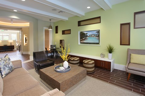 A living room with a brown couch, a coffee table, and a painting of a pool.