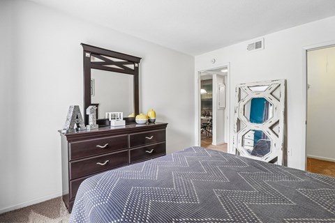 A bedroom with a large bed and a dresser with a mirror above it.