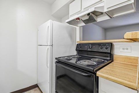 A black stove in a kitchen with a white fridge.