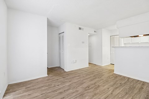 A spacious room with wooden flooring and white walls.