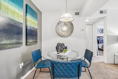 A modern dining room with a glass table and blue chairs.