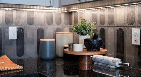 A kitchen counter with a bowl, a plant, and a rolling pin on it.