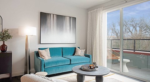 A blue couch sits in a living room with a large window.