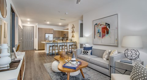 A modern living room with a grey sofa, a wooden coffee table, and a large abstract painting on the wall.
