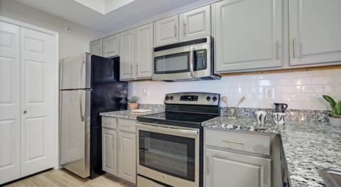A kitchen with white cabinets and appliances.