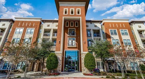 A building with a central entrance and a row of trees in front.
