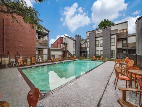 A swimming pool surrounded by chairs and buildings.