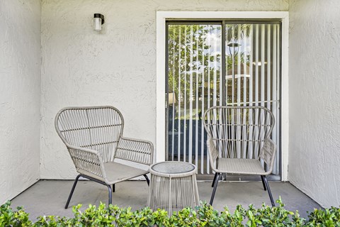 Two chairs and a table are on a patio.