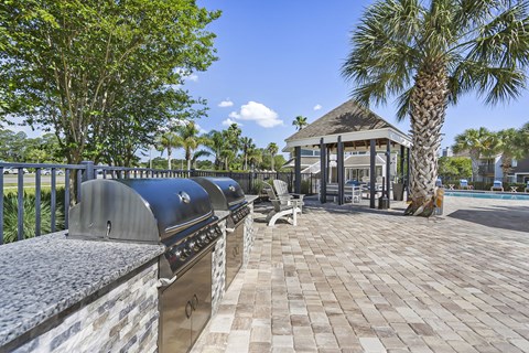 A gazebo is surrounded by a brick walkway and palm trees.