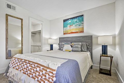 A bedroom with a large bed and a painting on the wall.