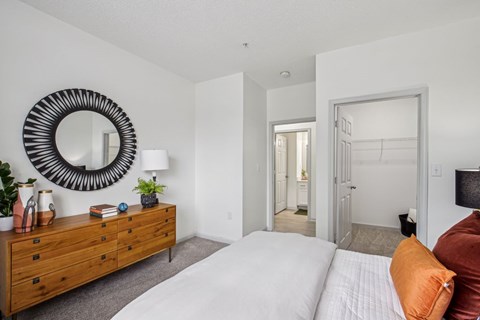 A bedroom with a white bed and a wooden dresser.