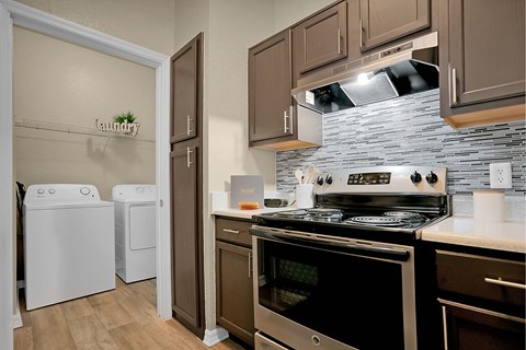 A kitchen with a stove top oven and a washer and dryer.