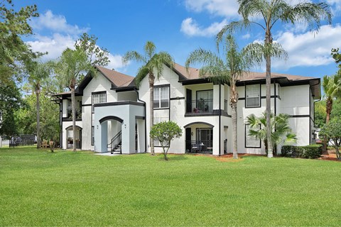 A large white house with a black roof and a green lawn in front.
