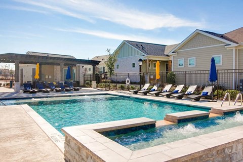 A swimming pool with a stone border and sun loungers.