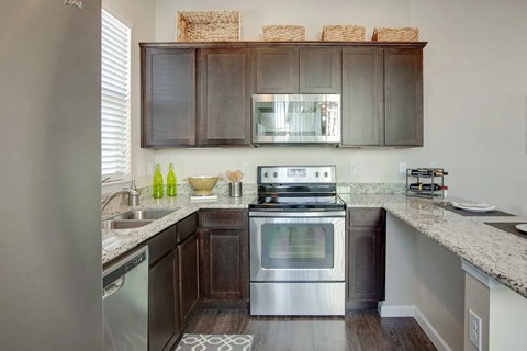 A modern kitchen with dark wood cabinets and stainless steel appliances.