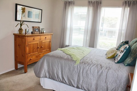 A bedroom with a bed, dresser, and window.