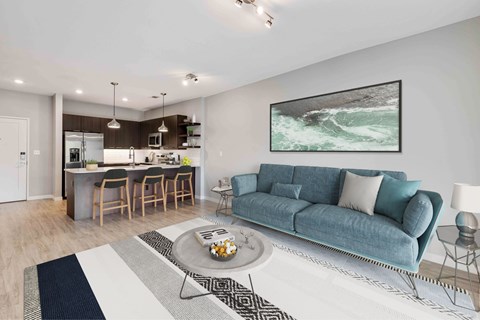 A modern living room with a blue couch and a painting of a wave on the wall.