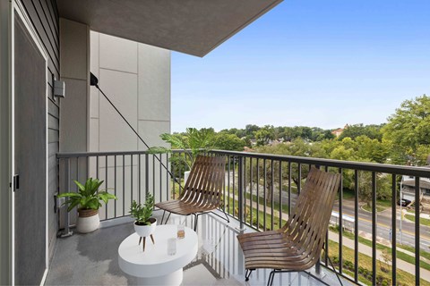 A balcony with a table and two chairs overlooking a street.
