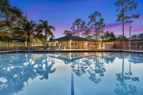 A pool with a building and trees in the background.