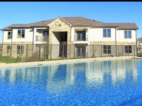 A large house with a pool in front.