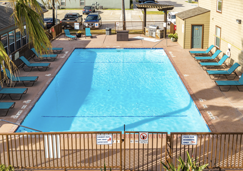 A pool surrounded by chairs and a fence.