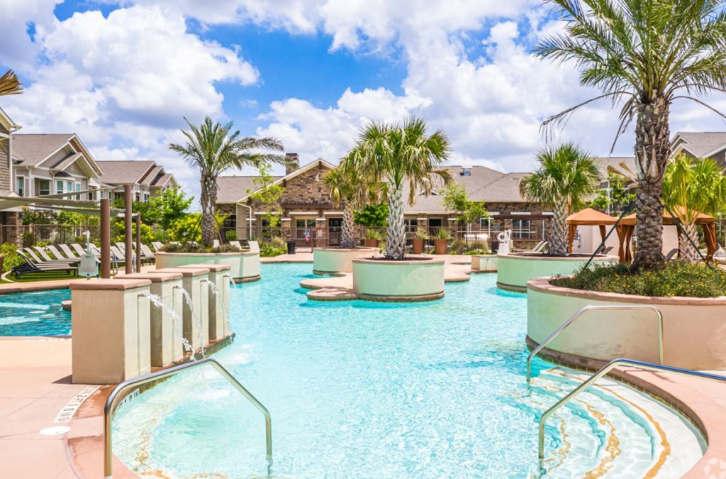 Resort inspired pool with lush palm trees and fountains