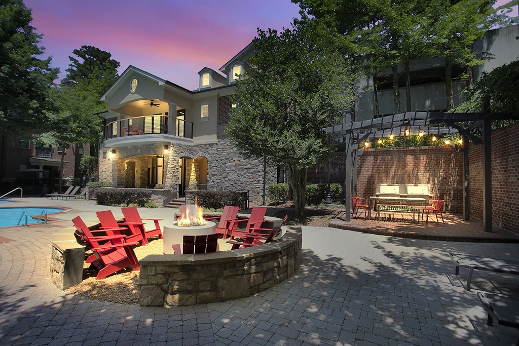 a backyard patio with a fire pit and chairs