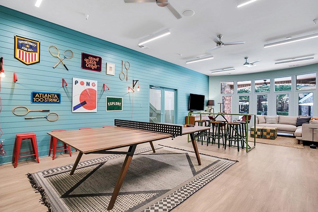 a common room with a ping pong table and chairs and a blue wall with