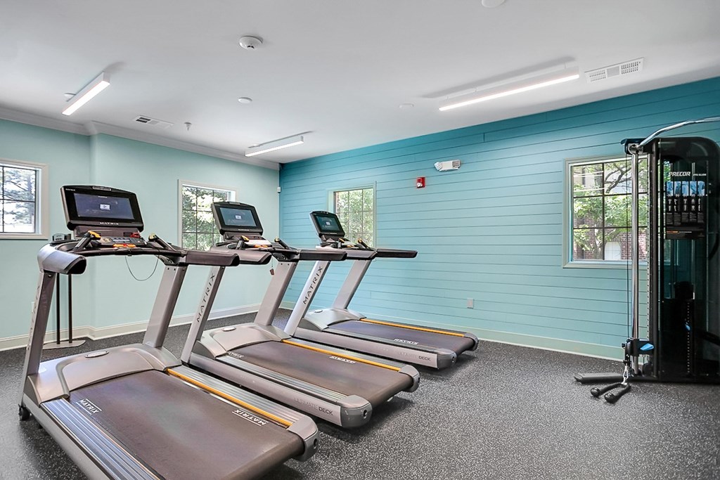four treadmills in a gym with blue walls and cardio equipment