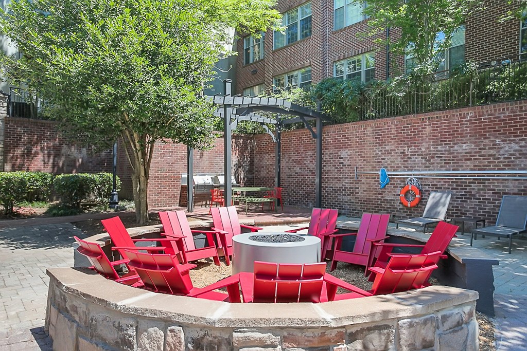 an outdoor patio with red chairs and a fire pit