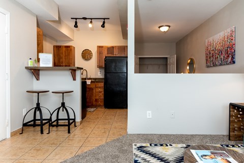 A kitchen with a black refrigerator and wooden cabinets.