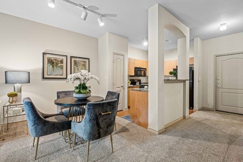 A dining room with a table set for two and a carpeted floor.