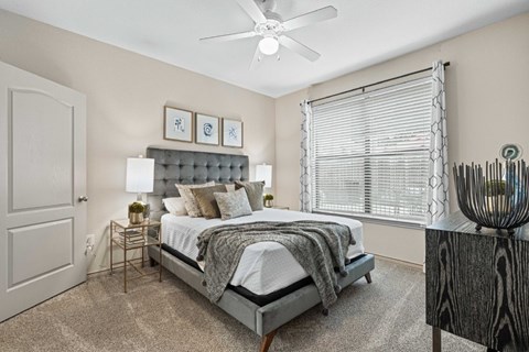 A bedroom with a bed, nightstand, and a ceiling fan.