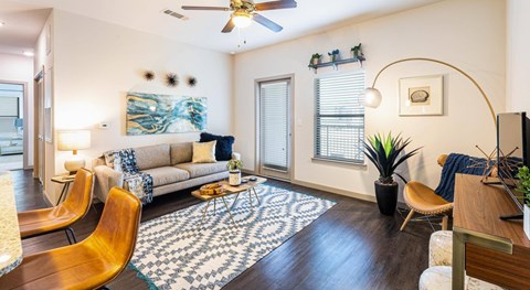 A living room with a patterned rug and a ceiling fan.