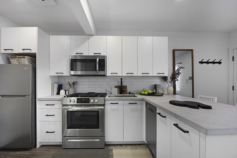 A modern kitchen with white cabinets and stainless steel appliances.