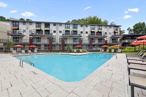A large swimming pool in front of a multi-story apartment building.