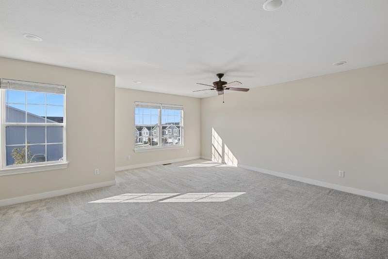A spacious room with a ceiling fan and large windows.