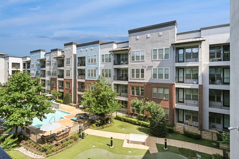 Apartment complex with a pool and green lawn.