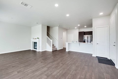 A spacious living room with wood flooring and a staircase leading to the upper level.