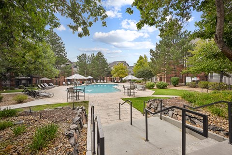 A pool surrounded by trees and a stone wall.