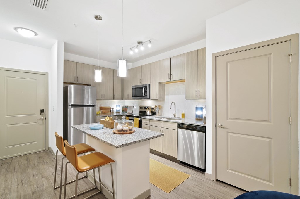 a kitchen with stainless steel appliances and a bar with two chairs