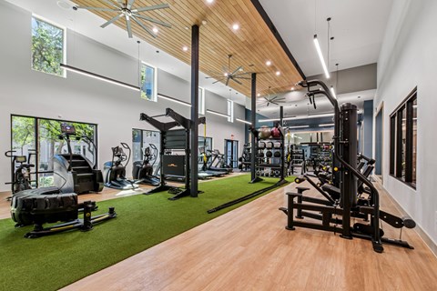 A gym with a variety of equipment including treadmills, weights, and exercise machines.