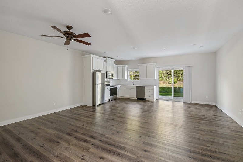 A room with a ceiling fan and wooden flooring.