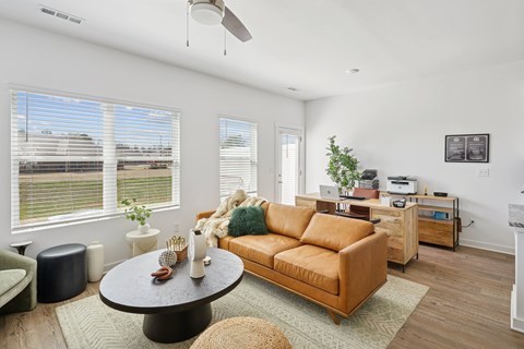 A living room with a brown couch and a round table.