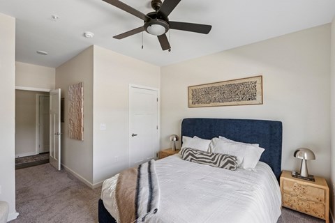 A bedroom with a large bed and a ceiling fan.